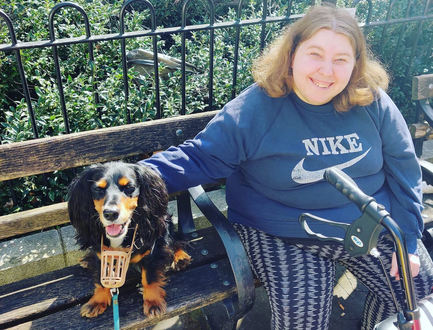 Photo of Dog Guizmo and our service user Christina smiling on a bench